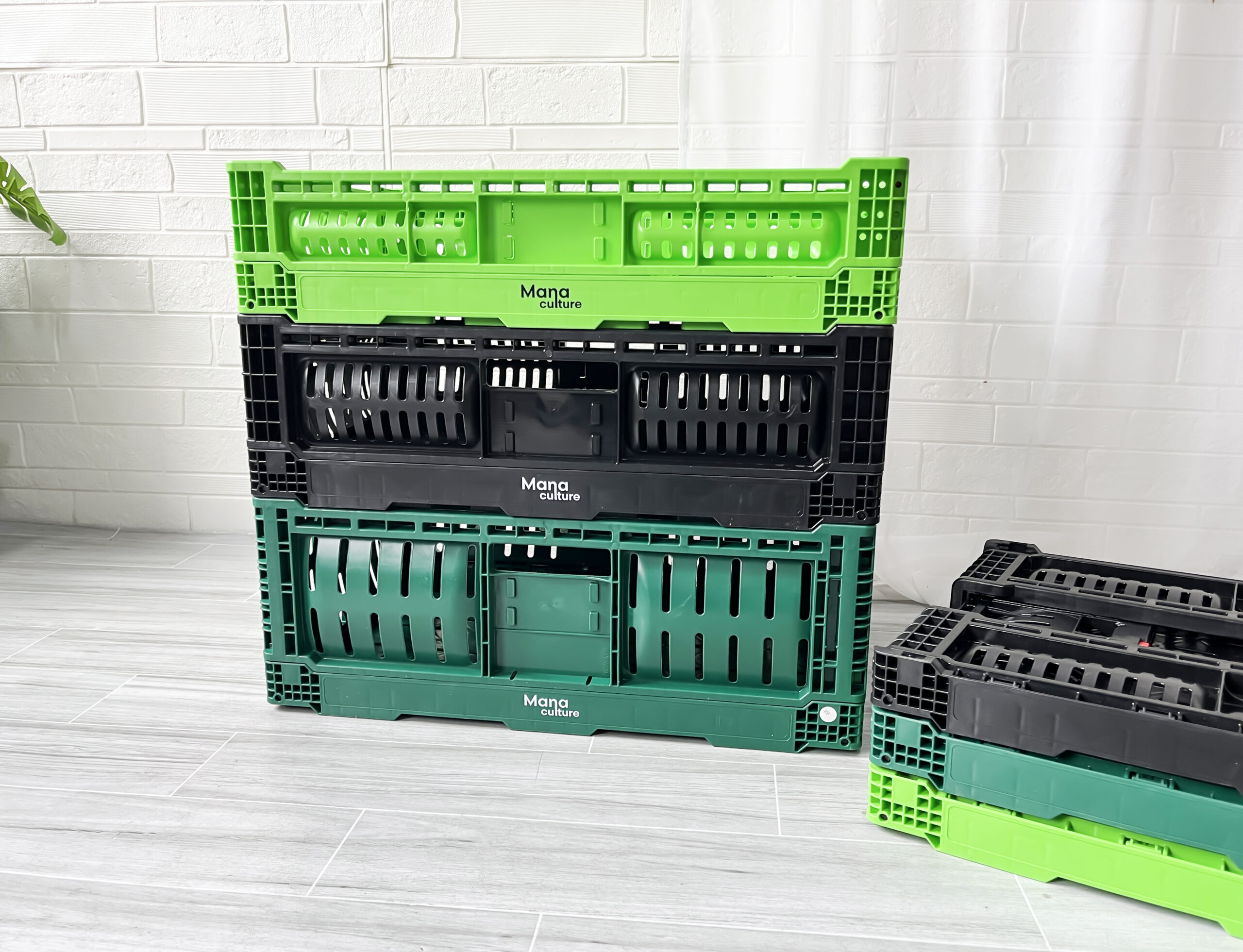 Trois caisses en plastique vertes et noires posées sur un plancher en bois.
