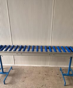 Un convoyeur à rouleaux bleu assis sur le dessus d'un sol en béton.
